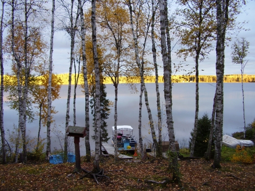 The setting sun casts a golden glow on the far shore illuminating the treeline. A picture perfect end to a great day on the lake.