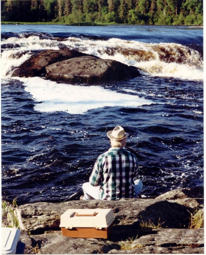 A solitary anlger enjoying his Canadian fishing vacation, tries his luck at catching a trophy fish in one of the fast moving rivers.